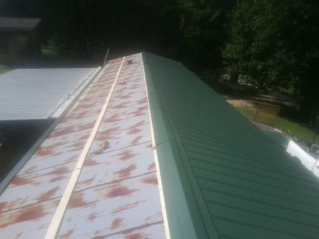 Old rusted panels beside newly installed green metal roofing — Wind Damage Roof Repair by Roofing Brothers in Eagle Rock