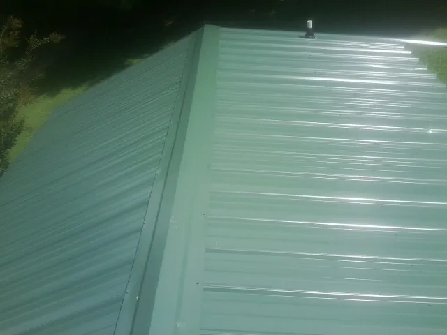 New green metal panels meeting at the ridge of a roof — Flat Roof Repair work by our crew in Eagle Rock