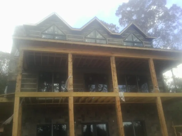 Dormers and porch framing on a large log home under construction — Roof Coating work by our crew in Eagle Rock
