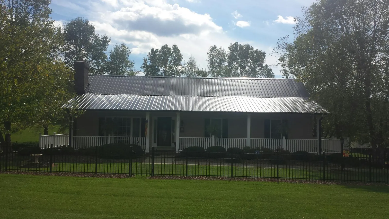 Gray metal roof on a brick ranch with a full width front porch — Gutter Guard Installation work by our crew in Eagle Rock