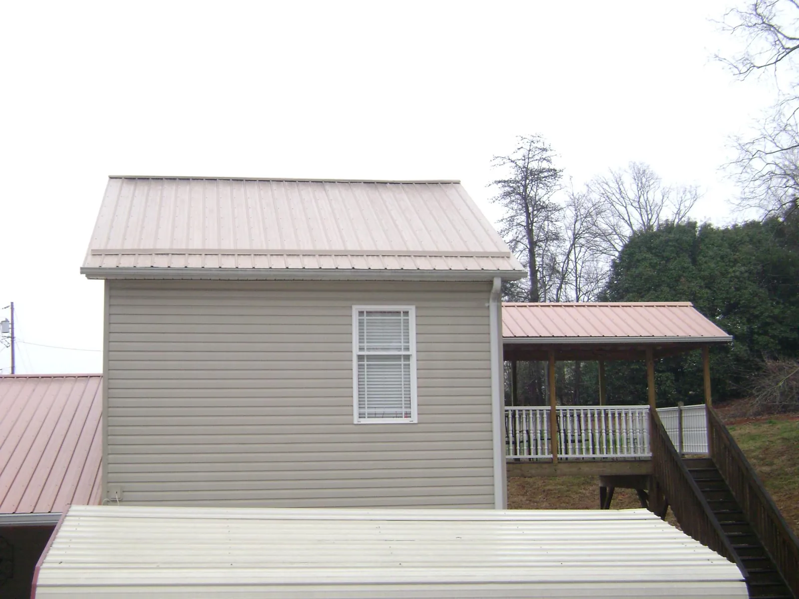 Tan metal roofs on a two story addition and attached porch, from a Roof Replacement job in Eagle Rock